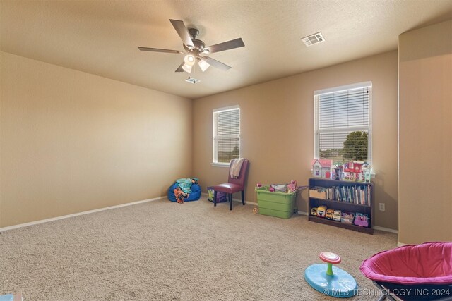 game room with carpet floors, ceiling fan, and a textured ceiling