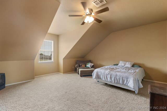 bedroom featuring a textured ceiling, ceiling fan, vaulted ceiling, and carpet