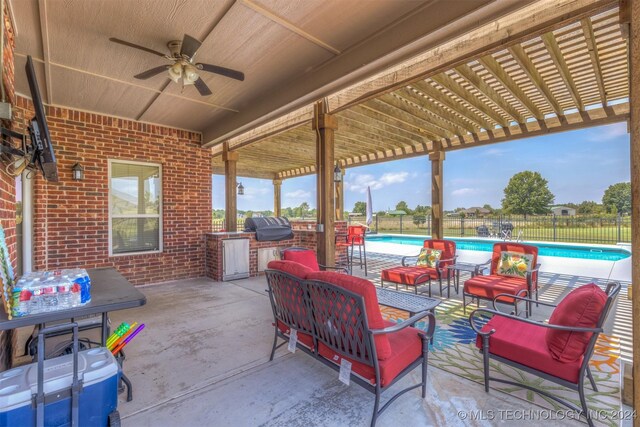 view of patio featuring an outdoor hangout area, a fenced in pool, exterior kitchen, ceiling fan, and grilling area