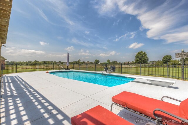 view of swimming pool with a lawn, a diving board, and a patio area