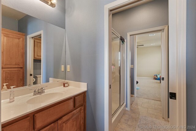 bathroom featuring tile patterned floors, an enclosed shower, and vanity