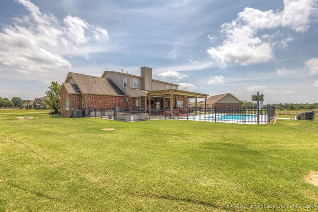 back of property with a pergola, central AC unit, a patio area, and a yard