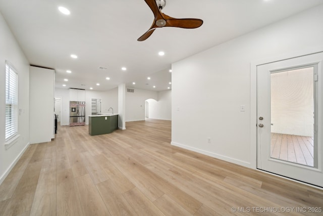 unfurnished living room with ceiling fan and light wood-type flooring