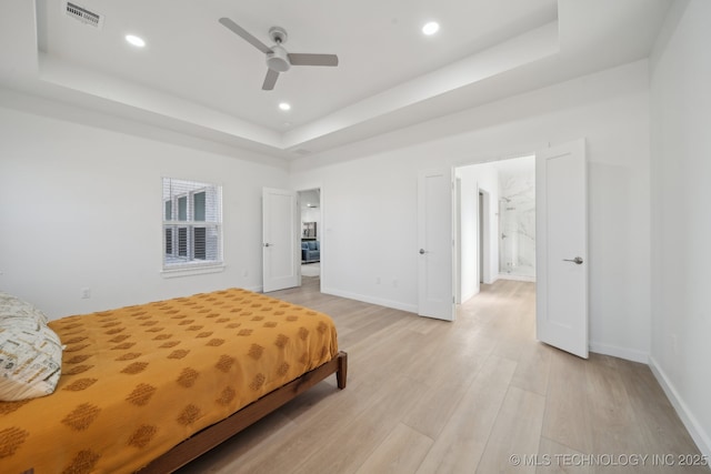 bedroom with light hardwood / wood-style flooring, a raised ceiling, and ceiling fan