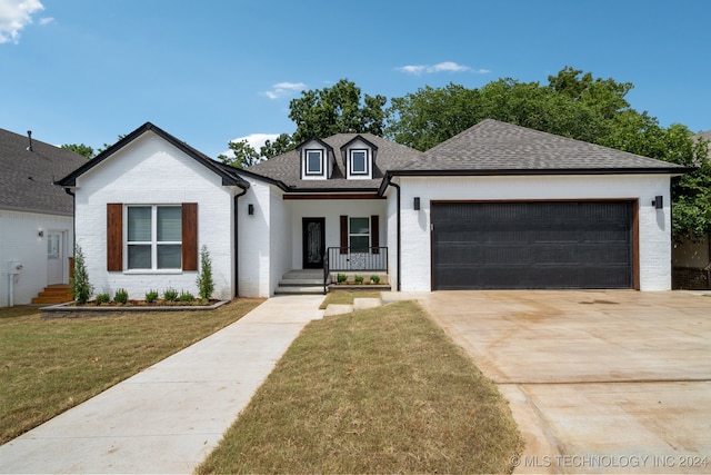 view of front of property with a front lawn, covered porch, and a garage