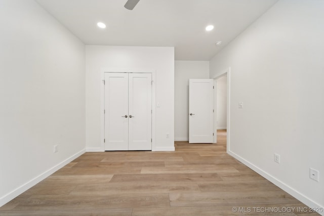 unfurnished bedroom featuring ceiling fan, a closet, and light hardwood / wood-style flooring