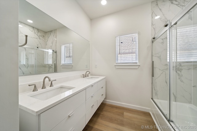 bathroom with hardwood / wood-style flooring, vanity, and bath / shower combo with glass door