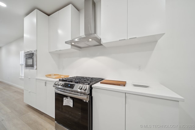 kitchen featuring white cabinets, stainless steel gas range, and wall chimney exhaust hood