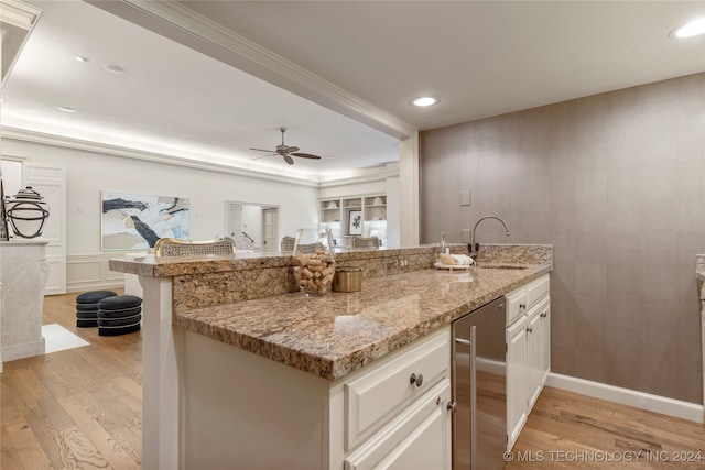 kitchen with ceiling fan, light wood-type flooring, white cabinetry, light stone countertops, and sink