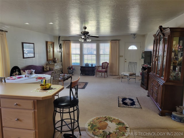 dining space featuring ceiling fan, light carpet, and a textured ceiling