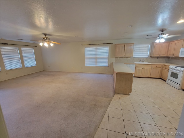 kitchen featuring light brown cabinets, light carpet, sink, and white appliances