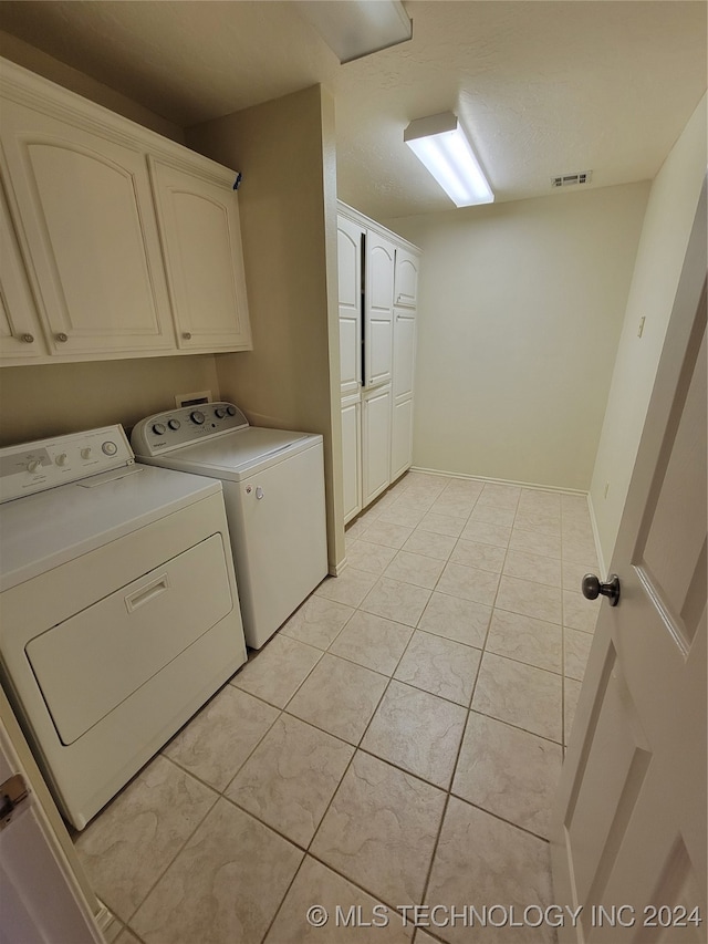 washroom featuring cabinets, separate washer and dryer, and light tile patterned floors