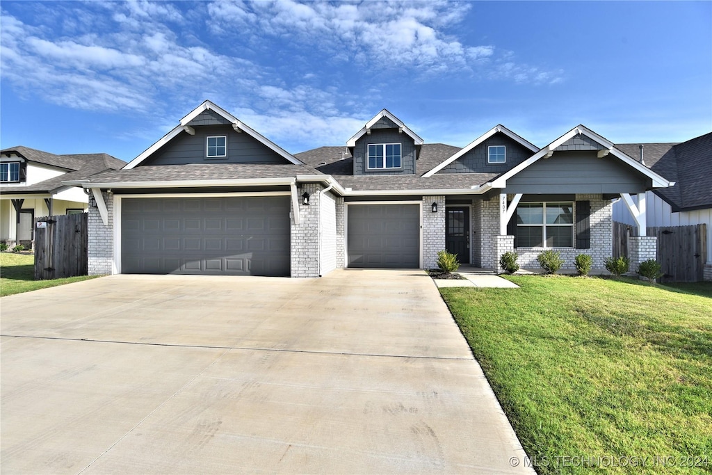 craftsman house with a garage, brick siding, fence, driveway, and a front yard