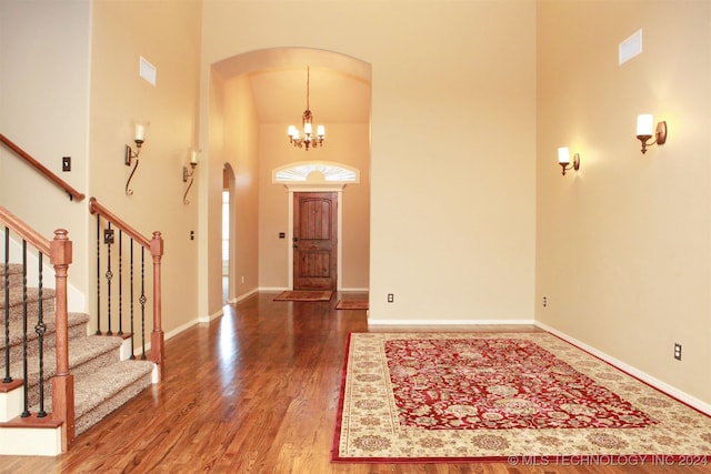 foyer featuring hardwood / wood-style floors, a towering ceiling, and an inviting chandelier