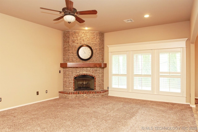 unfurnished living room with ceiling fan, carpet flooring, and a stone fireplace