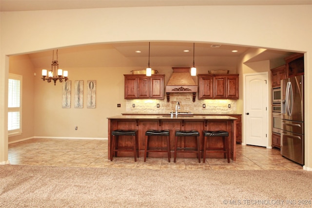 kitchen featuring premium range hood, light colored carpet, hanging light fixtures, a breakfast bar, and stainless steel appliances