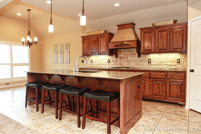 kitchen featuring light tile patterned flooring, a center island with sink, and premium range hood