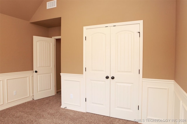 unfurnished bedroom with vaulted ceiling, light colored carpet, and a closet