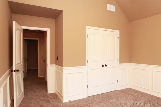 unfurnished bedroom with a closet, vaulted ceiling, and light carpet