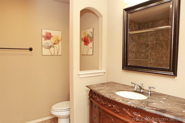 bathroom featuring a shower with door, vanity, and toilet