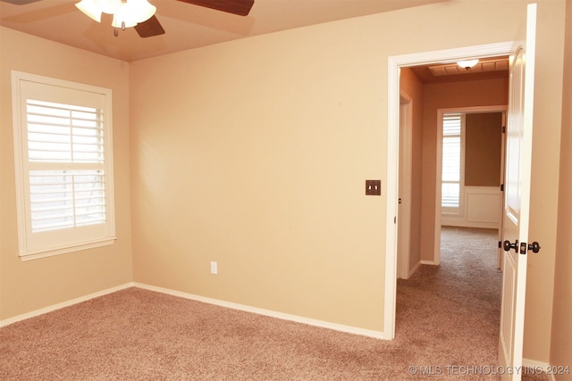 empty room featuring ceiling fan and light carpet