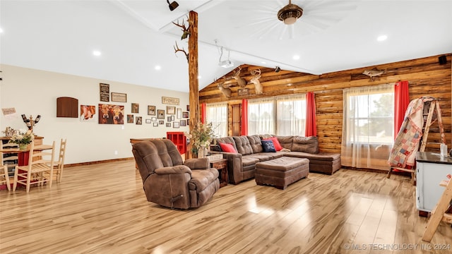 living room featuring ceiling fan, rustic walls, light hardwood / wood-style floors, rail lighting, and lofted ceiling with beams