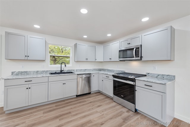 kitchen featuring gray cabinets, stainless steel appliances, sink, and light hardwood / wood-style floors