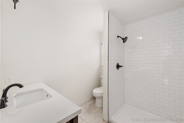 bathroom featuring tile patterned flooring, vanity, toilet, and a tile shower