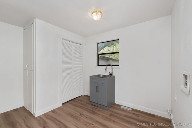 unfurnished bedroom with hardwood / wood-style floors, sink, and a closet