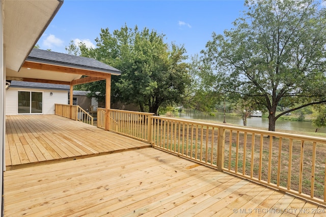 wooden terrace featuring a water view and a yard