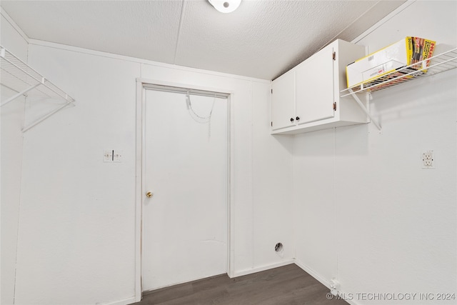 clothes washing area featuring dark wood-type flooring, cabinets, and a textured ceiling