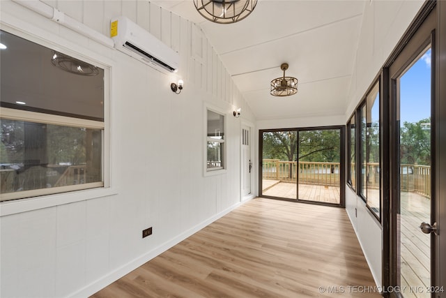 unfurnished sunroom featuring a wall mounted AC and vaulted ceiling