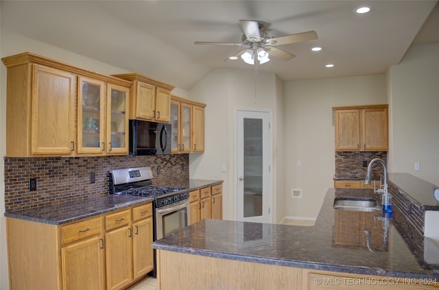 kitchen with gas stove, kitchen peninsula, sink, ceiling fan, and dark stone counters