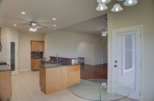 kitchen with ceiling fan with notable chandelier, decorative light fixtures, tasteful backsplash, light hardwood / wood-style floors, and sink