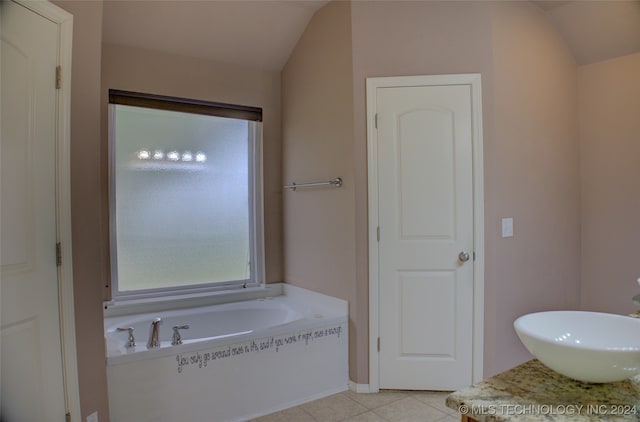 bathroom featuring vanity, vaulted ceiling, tile patterned floors, and tiled bath