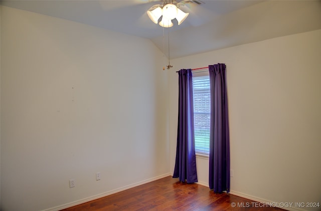 empty room with lofted ceiling, ceiling fan, and dark hardwood / wood-style floors