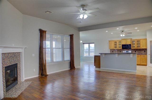 kitchen featuring tasteful backsplash, visible vents, light wood-type flooring, a fireplace, and black microwave