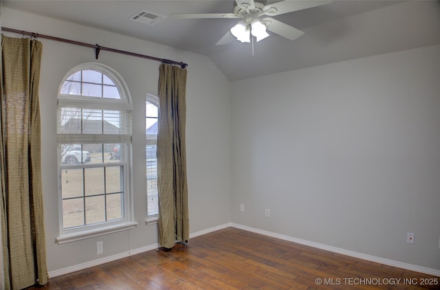 unfurnished room featuring lofted ceiling, dark wood-style flooring, a ceiling fan, visible vents, and baseboards