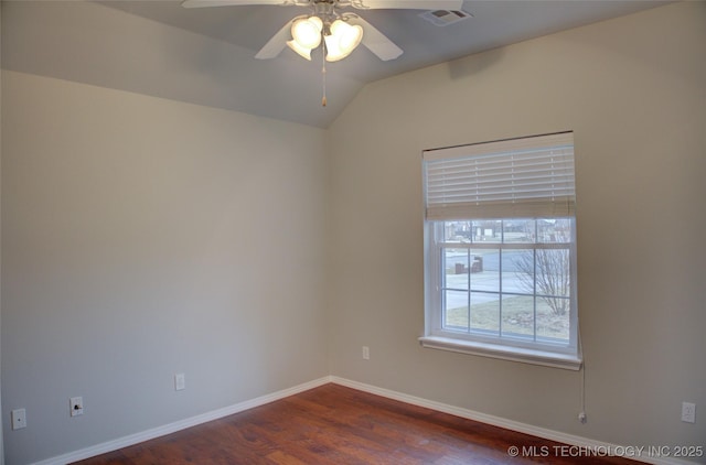 spare room featuring baseboards, visible vents, lofted ceiling, dark wood-style floors, and ceiling fan