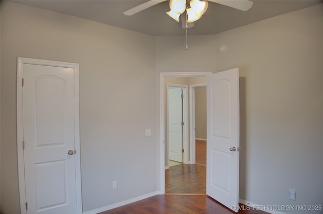 unfurnished bedroom with a ceiling fan, baseboards, and dark wood-style flooring