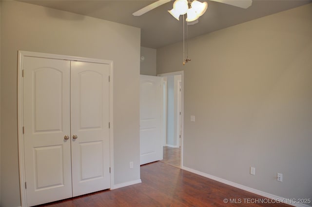 unfurnished bedroom featuring a closet, dark wood finished floors, baseboards, and ceiling fan