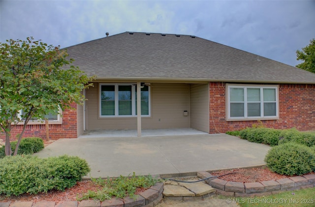 rear view of house with a patio area, brick siding, and a shingled roof