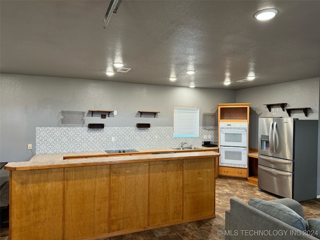 kitchen featuring decorative backsplash, dark wood-type flooring, stainless steel refrigerator with ice dispenser, black electric cooktop, and white double oven