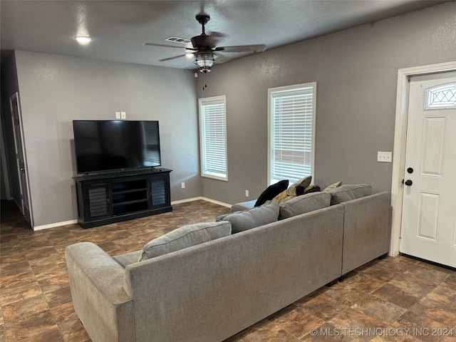 tiled living room with ceiling fan and a textured ceiling