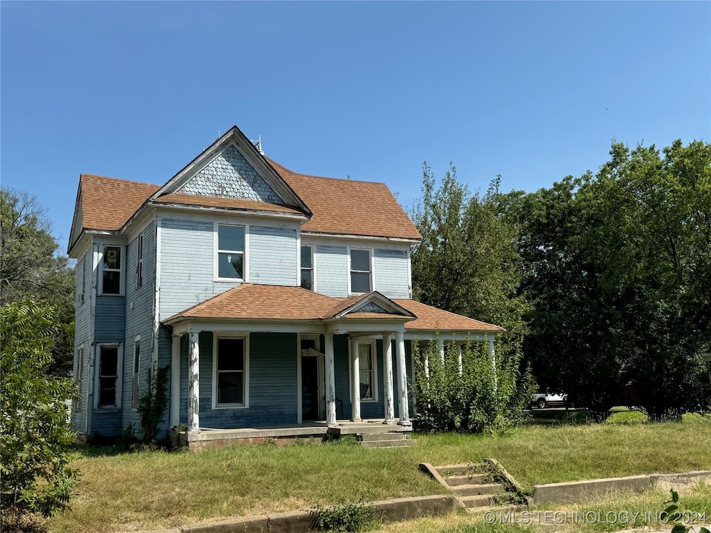 victorian house with a shingled roof, covered porch, and a front lawn