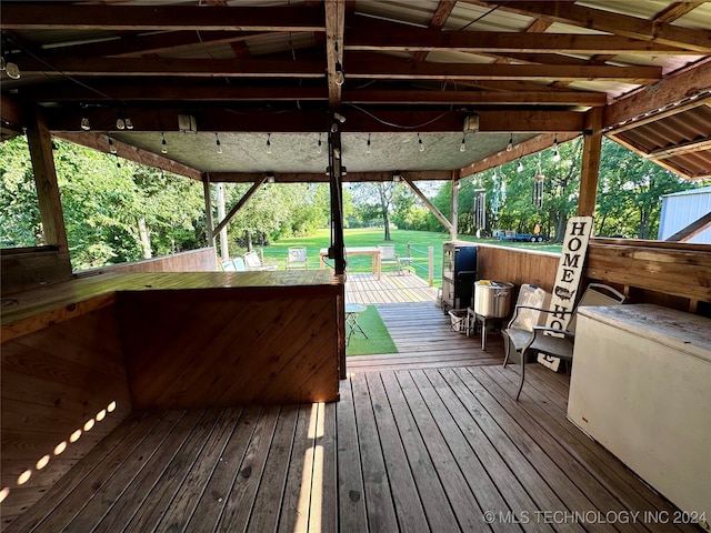 wooden terrace featuring an outdoor bar and a lawn