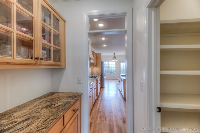 kitchen with light hardwood / wood-style floors, dark stone countertops, and ornamental molding