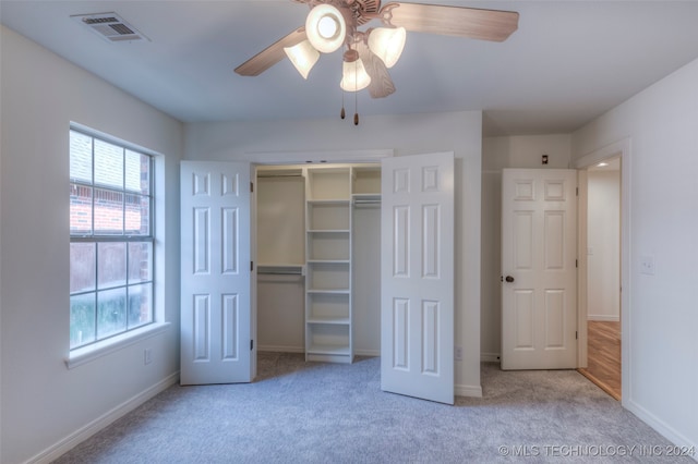 unfurnished bedroom featuring ceiling fan, light colored carpet, and a closet