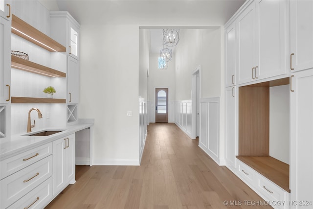 hallway with sink, light hardwood / wood-style flooring, and a high ceiling