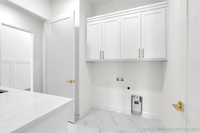 laundry room with hookup for an electric dryer, cabinets, hookup for a washing machine, and light tile patterned floors